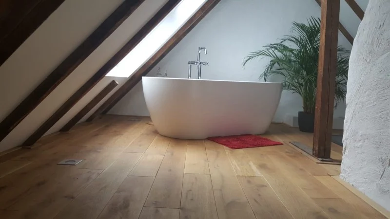 Helles Badezimmer unter einer Dachschräge mit warmem Holzfußboden